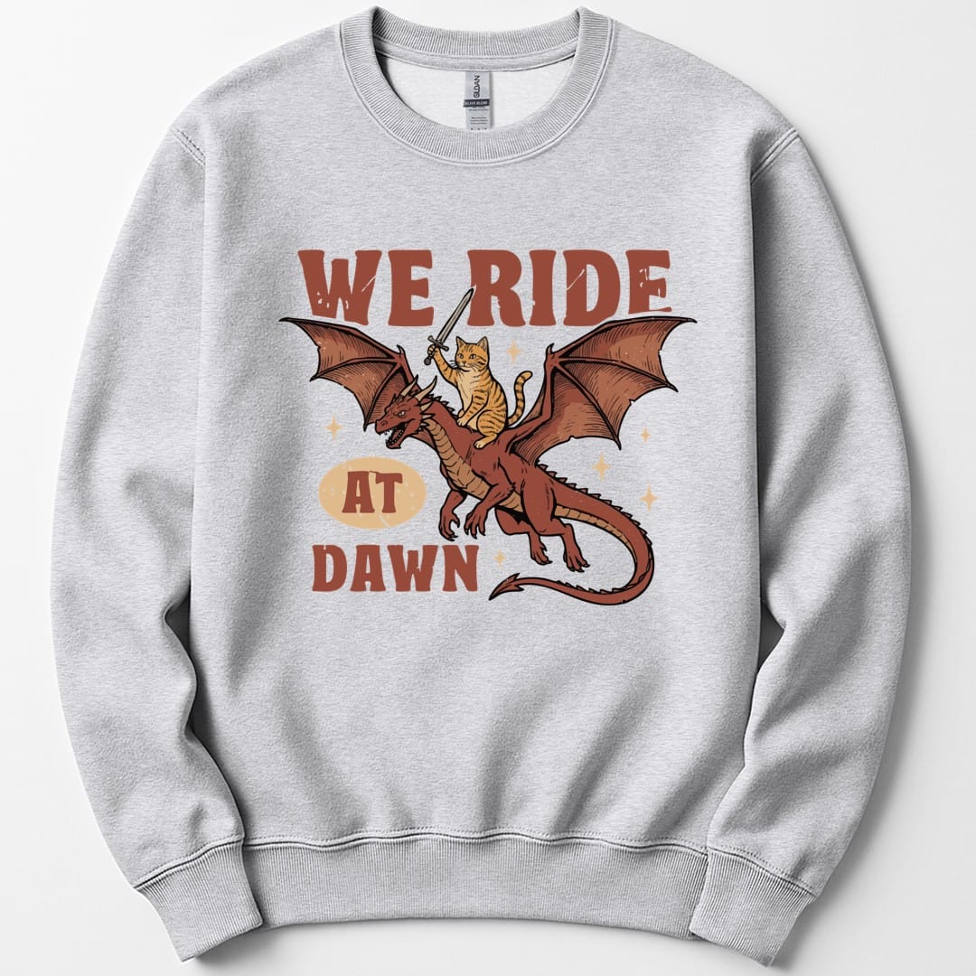 The same We Ride At Dawn dragon cat design, on an ash sweatshirt.