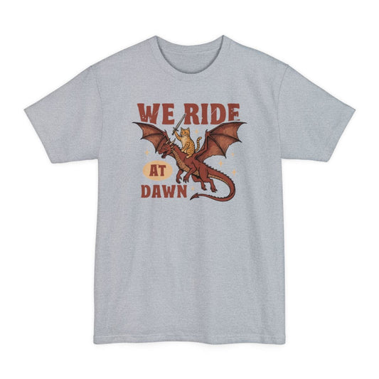 Light Steel tall t-shirt. Reads "We ride" across the top in red capitals and "At dawn" across the bottom, with "at dawn" partly inside a cream oval. Between them a ginger tabby cat rides on the back of a red dragon in flight, holding a tiny sword aloft. Retro cartoon style.