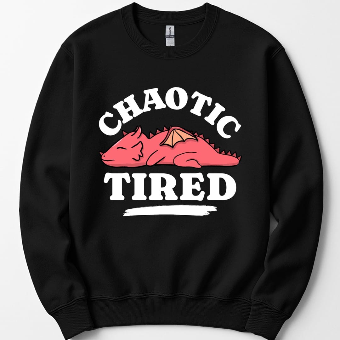 Black sweatshirt. Reads "Chaotic" curving across the top and "Tired" across the bottom in chunky white capitals. Between them a round pink dragon lies curled up fast asleep, eyes shut, wings folded, with a rough white brush stroke underneath it. Simple cartoon style in pink and white.