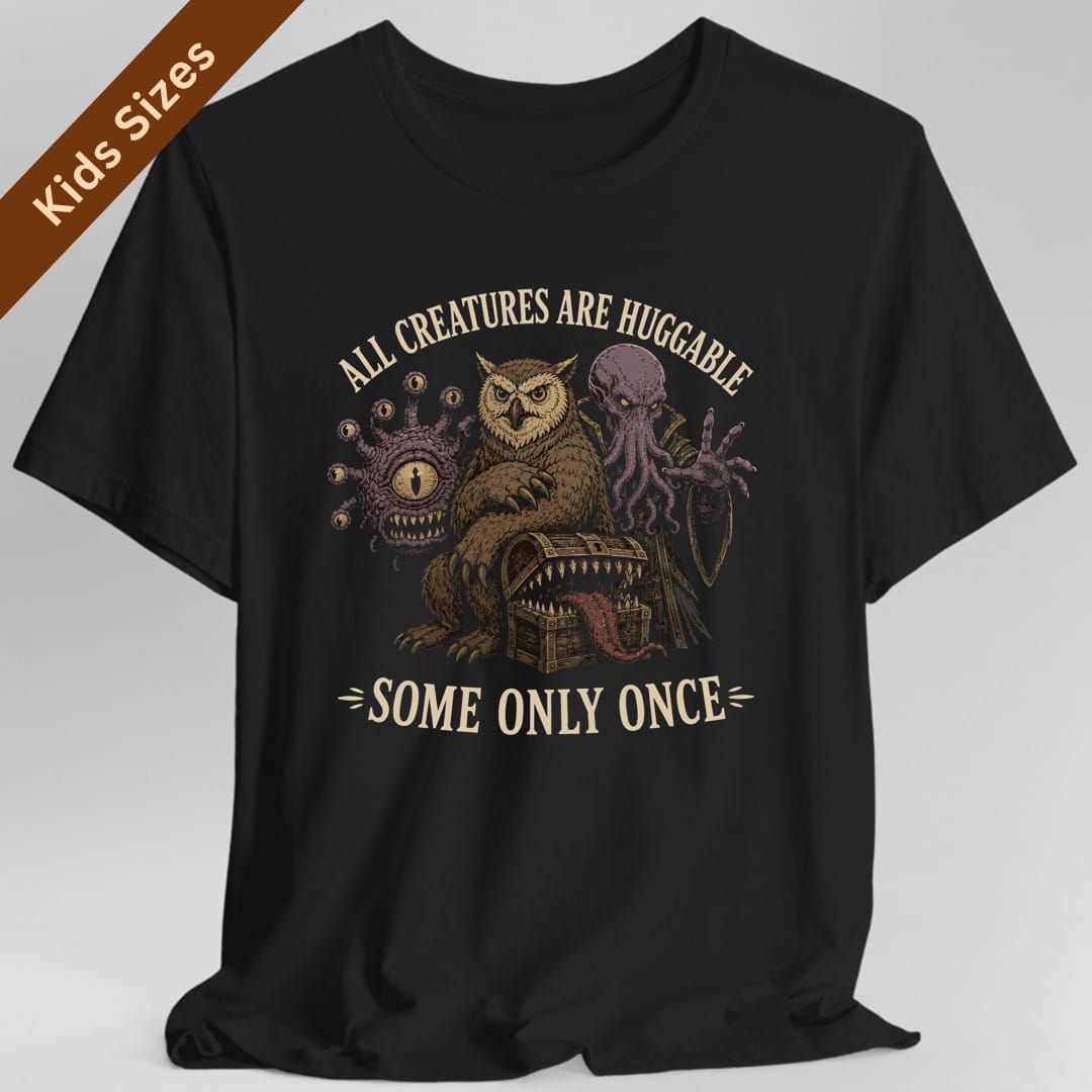 Black kids t-shirt. Reads "All creatures are huggable" curving across the top and "Some only once" across the bottom. Between them a beholder, an owlbear, a mimic chest and a tentacled creature huddle together in a group. Finely engraved illustration in muted browns, purple and cream.