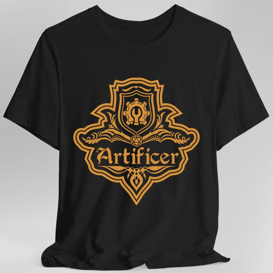 Black t-shirt. A crest shaped like a shield with scalloped edges, drawn entirely in amber orange with no other color. A small inner shield at the top carries a cogwheel with a keyhole, an open book with a twenty-sided die on it sits across the middle, and a banner below reads "Artificer" in an ornate blackletter script. A pointed pendant hangs from the bottom.