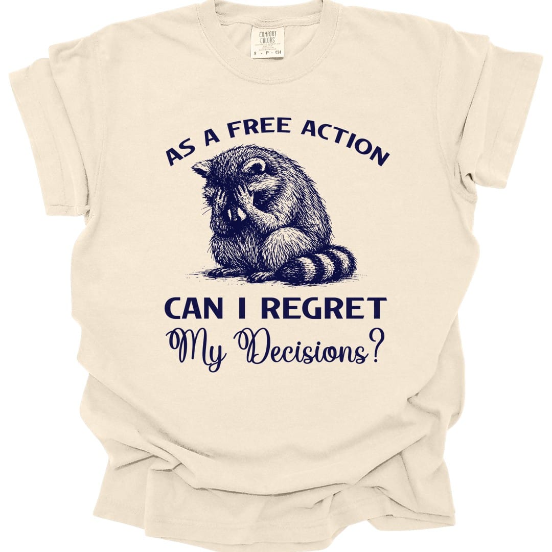 Ivory t-shirt. Reads "As a free action" curving across the top and "Can I regret my decisions?" across the bottom in navy capitals and script. Between them a raccoon lies slumped on its front, chin on the ground, looking thoroughly defeated.