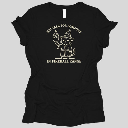 Black women's t-shirt. Reads "Big talk for someone" curving across the top and "In fireball range" across the bottom in cream capitals. Between them a cat stands upright in a starry pointed hat and robe, looking unimpressed, holding up a small flame in one paw.