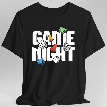 Black t-shirt. Reads "Game Night" in very large white block capitals across two lines. Scattered over and between the letters sit board game pieces: a green meeple, a blue meeple, a red pawn, a yellow pawn and three white dice. Nothing else on the shirt.