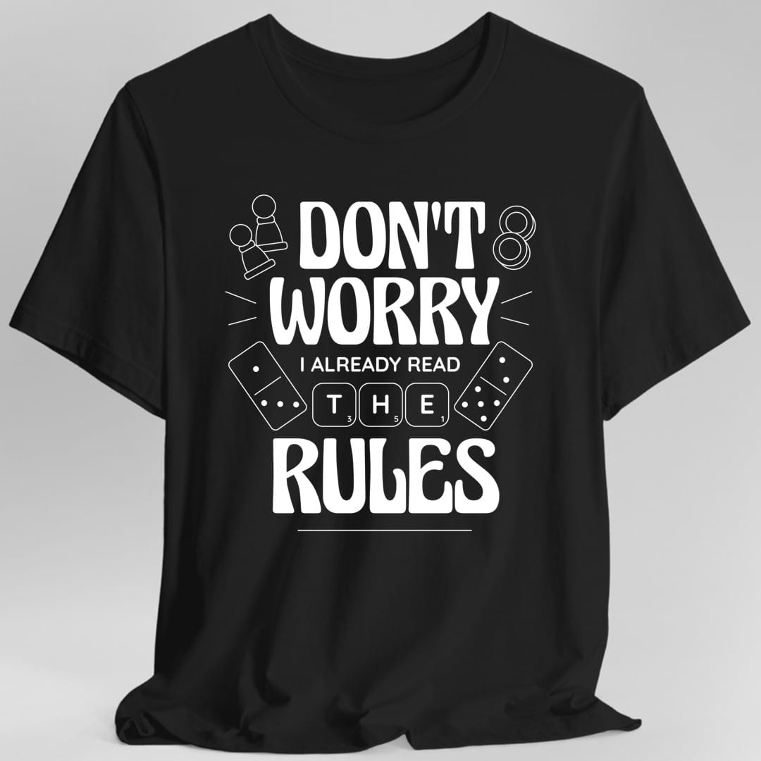 Black t-shirt. Reads "Don't worry" in large white capitals, then "I already read" in small type, then "The" with a domino tile either side, and "Rules" in large capitals at the bottom. A small meeple sits top left and a domino top right. All white.