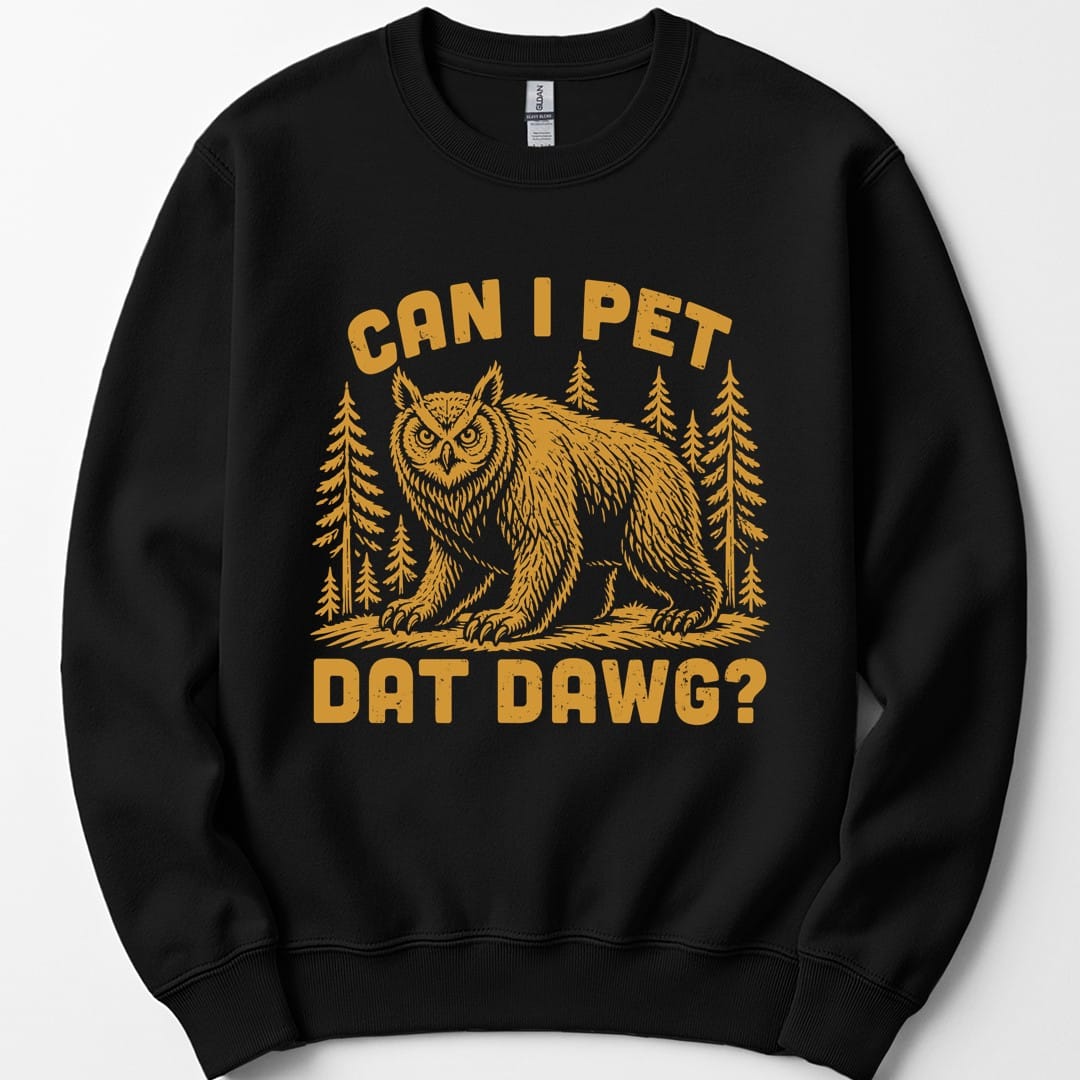 Black sweatshirt. The design reads "Can I pet dat dawg?" in chunky arched capitals, split above and below the picture. Between them a shaggy owlbear, part great horned owl and part bear, stands on all fours on a patch of ground with tall pine trees behind it. Retro woodcut style, printed in a single warm gold ink.