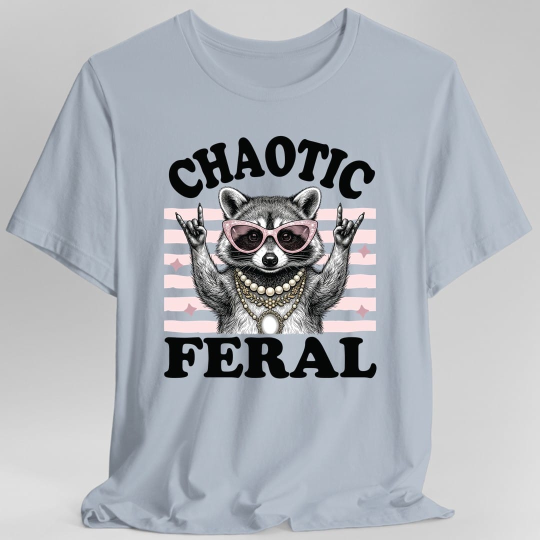 Light Blue t-shirt. Reads "Chaotic" curving across the top and "Feral" across the bottom in fat black retro capitals. Between them a raccoon in pink cat-eye sunglasses and a pearl necklace throws both hands up in rock horns, with pale pink stripes and sparkles behind it. Engraved linework with flat pink and black.