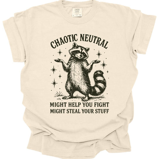 Ivory t-shirt. Reads "Chaotic Neutral" curving across the top in dark green capitals. Below, a raccoon stands upright with both paws spread in a shrug, drawn in fine engraving lines and ringed with sparkles. At the bottom, "Might help you fight, might steal your stuff." One dark green ink.