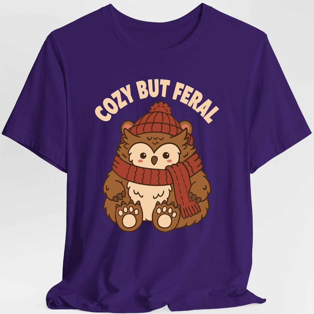 The same Cozy But Feral owlbear design, on a purple t-shirt.