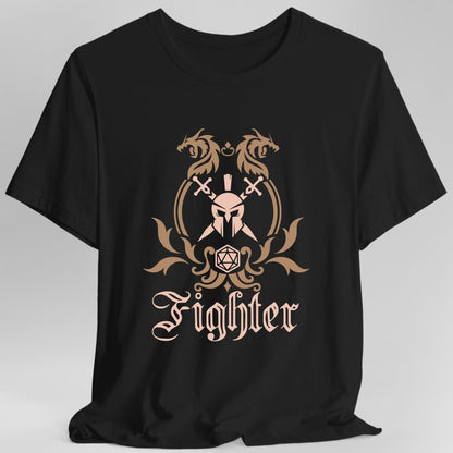 Black t-shirt. A heraldic crest drawn entirely in copper and tan on a plain background. Two dragons face each other over an arched frame, a helm behind crossed swords sits inside the arch, and a twenty-sided die hangs below it between leafy flourishes. Underneath, "Fighter" in an ornate blackletter script.