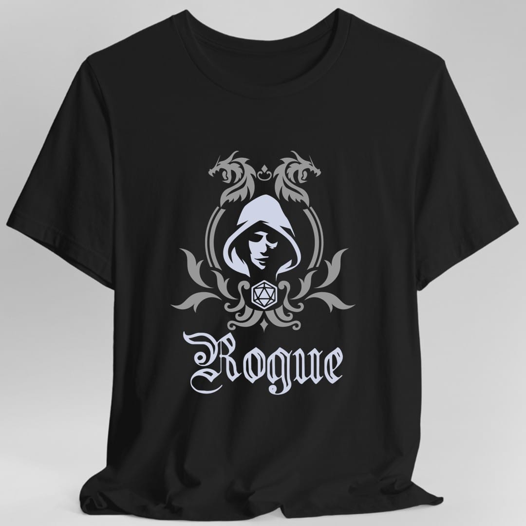 Black t-shirt. A heraldic crest drawn entirely in silver gray on a plain background. Two dragons face each other over an arched frame, a hooded face in shadow sits inside the arch, and a twenty-sided die hangs below it between leafy flourishes. Underneath, "Rogue" in an ornate blackletter script.