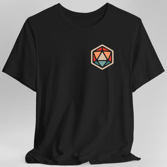 Black t-shirt. A single large twenty-sided die drawn as a flat geometric icon, its triangular facets picked out in coral red, orange, cream and pale teal against a tan outline. Very simple and graphic, with no numbers and no words.