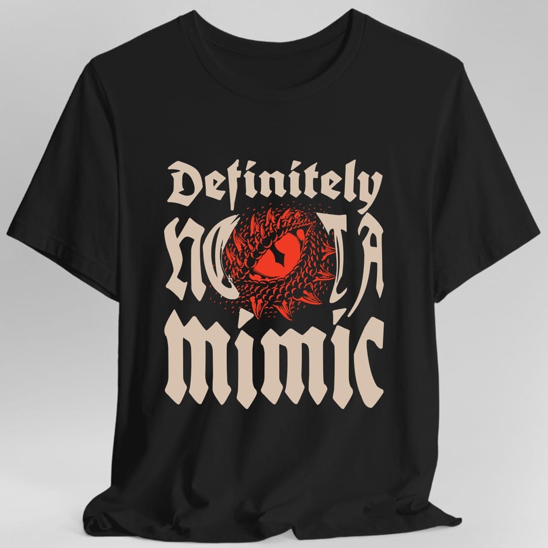 Black t-shirt. Reads "Definitely" in an ornate blackletter script at the top and "Not a mimic" beneath in the same style, all in cream. Behind the middle of the words, a red toothy maw with a single eye opens up, breaking through the lettering.