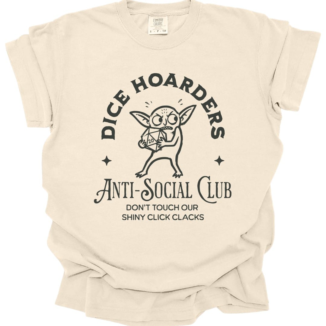 Ivory t-shirt. Reads "Dice hoarders" curving across the top and "Anti-social club" across the bottom in dark capitals, with "Don't touch our shiny click clacks" beneath. In the middle a goblin clutches a twenty-sided die to its chest, eyes wide, with a small star either side.