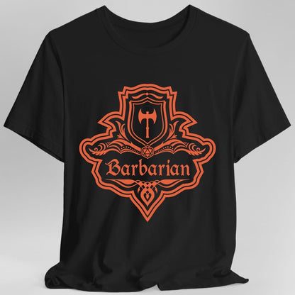 Black t-shirt. A crest shaped like a shield with scalloped edges, drawn entirely in burnt orange with no other color. A small inner shield at the top carries a single broad axe, an open book with a twenty-sided die on it sits across the middle, and a banner below reads "Barbarian" in an ornate blackletter script. A pointed pendant hangs from the bottom.