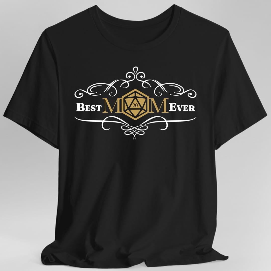 Black t-shirt. Reads "Best" and "Ever" either side of "MOM" in the centre, where the letter O is replaced by a gold twenty-sided die showing 20. Curling white filigree flourishes arch above and below the words. Small and centred, in white and gold.