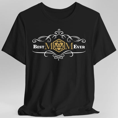 Black t-shirt. Reads "Best" and "Ever" either side of "MOM" in the centre, where the letter O is replaced by a gold twenty-sided die showing 20. Curling white filigree flourishes arch above and below the words. Small and centred, in white and gold.