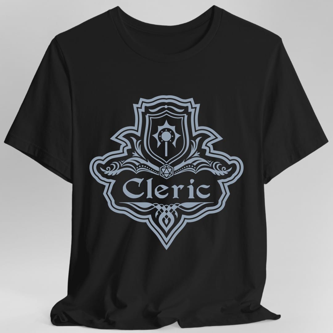 Black t-shirt. A crest shaped like a shield with scalloped edges, drawn entirely in pale slate blue with no other color. A small inner shield at the top carries a winged holy symbol, an open book with a twenty-sided die on it sits across the middle, and a banner below reads "Cleric" in an ornate blackletter script. A pointed pendant hangs from the bottom.