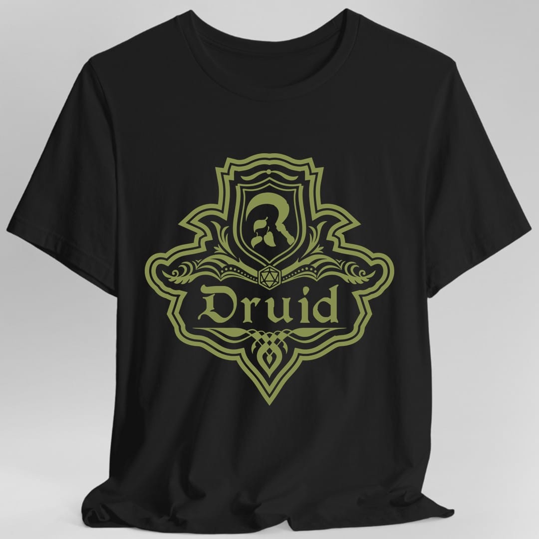 Black t-shirt. A crest shaped like a shield with scalloped edges, drawn entirely in olive green with no other color. A small inner shield at the top carries an antlered head, an open book with a twenty-sided die on it sits across the middle, and a banner below reads "Druid" in an ornate blackletter script. A pointed pendant hangs from the bottom.