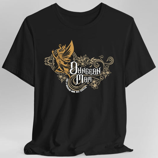Black t-shirt. Reads "Dungeon Mom" in an ornate white blackletter in the middle, with "Like a regular mom but cooler" in small capitals beneath. Behind the words a gold fairy with butterfly wings flies to the left, trailing curling gold flourishes and small flowers.