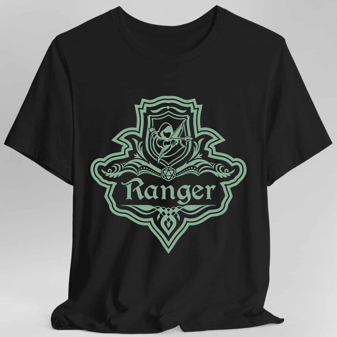 Black t-shirt. A crest shaped like a shield with scalloped edges, drawn entirely in sage green with no other color. A small inner shield at the top carries an archer drawing a bow, an open book with a twenty-sided die on it sits across the middle, and a banner below reads "Ranger" in an ornate blackletter script. A pointed pendant hangs from the bottom.