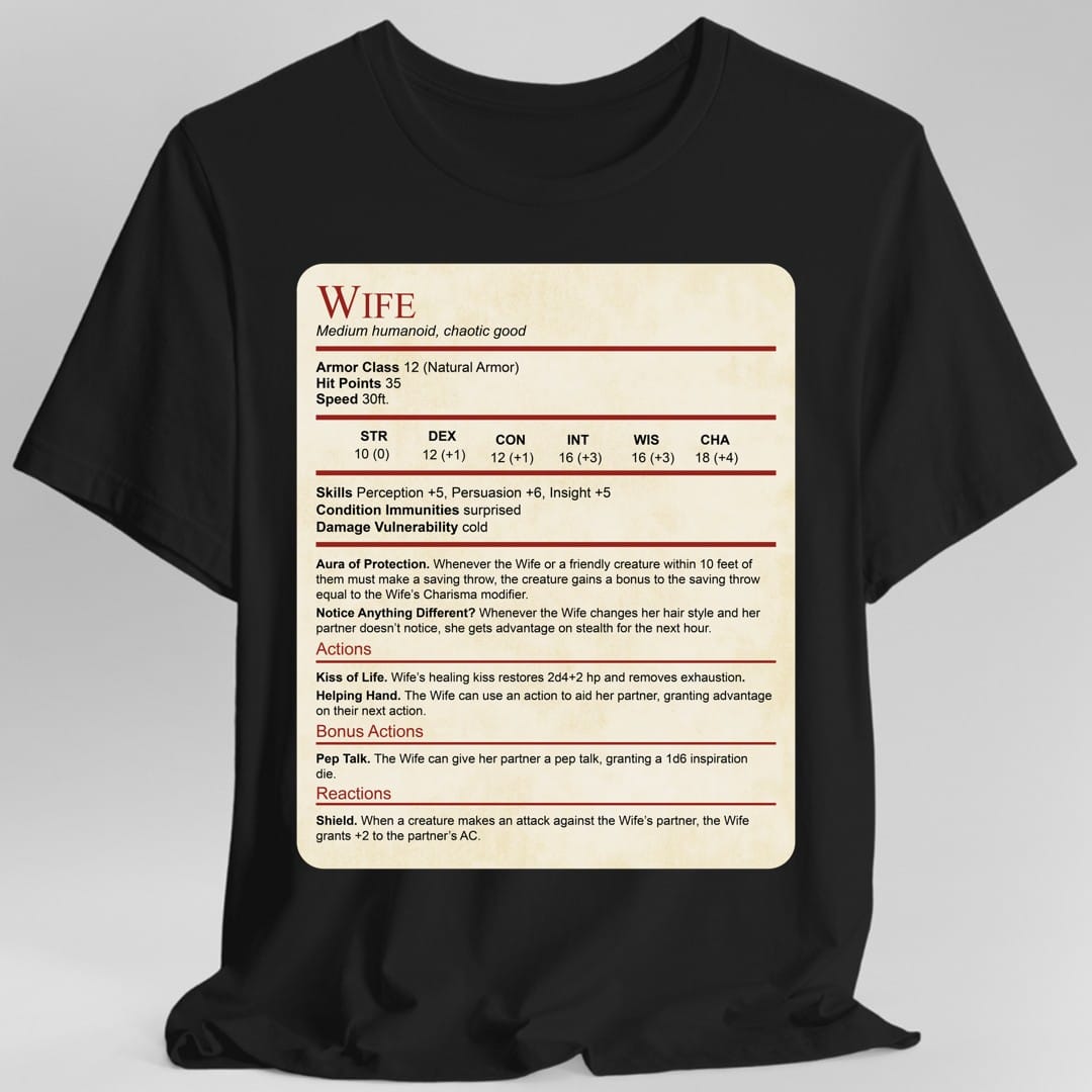 Black t-shirt. Laid out as a Dungeons and Dragons monster stat block on aged parchment, headed "Wife" in dark red with "Medium humanoid, chaotic good" beneath. It lists armor class 12, 35 hit points, speed 30 feet, a full row of ability scores, then Aura of Protection and Notice Anything Different, and actions named Kiss of Life, Helping Hand, Pep Talk and Shield. Dense small text in dark red and black on cream.