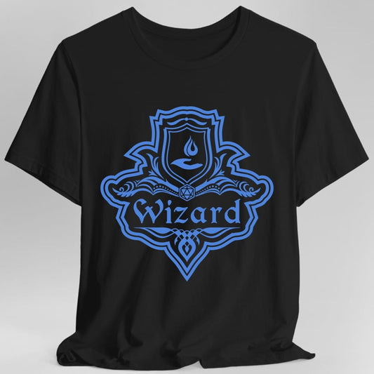 Black t-shirt. A crest shaped like a shield with scalloped edges, drawn entirely in cornflower blue with no other color. A small inner shield at the top carries a flame in a cupped hand, an open book with a twenty-sided die on it sits across the middle, and a banner below reads "Wizard" in an ornate blackletter script. A pointed pendant hangs from the bottom.