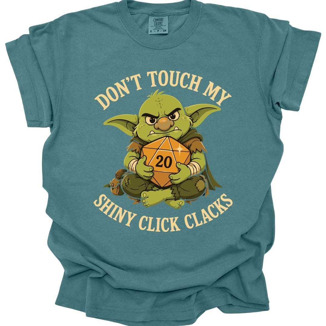 The same Don't Touch My Shiny Click Clacks design, on a blue spruce t-shirt.