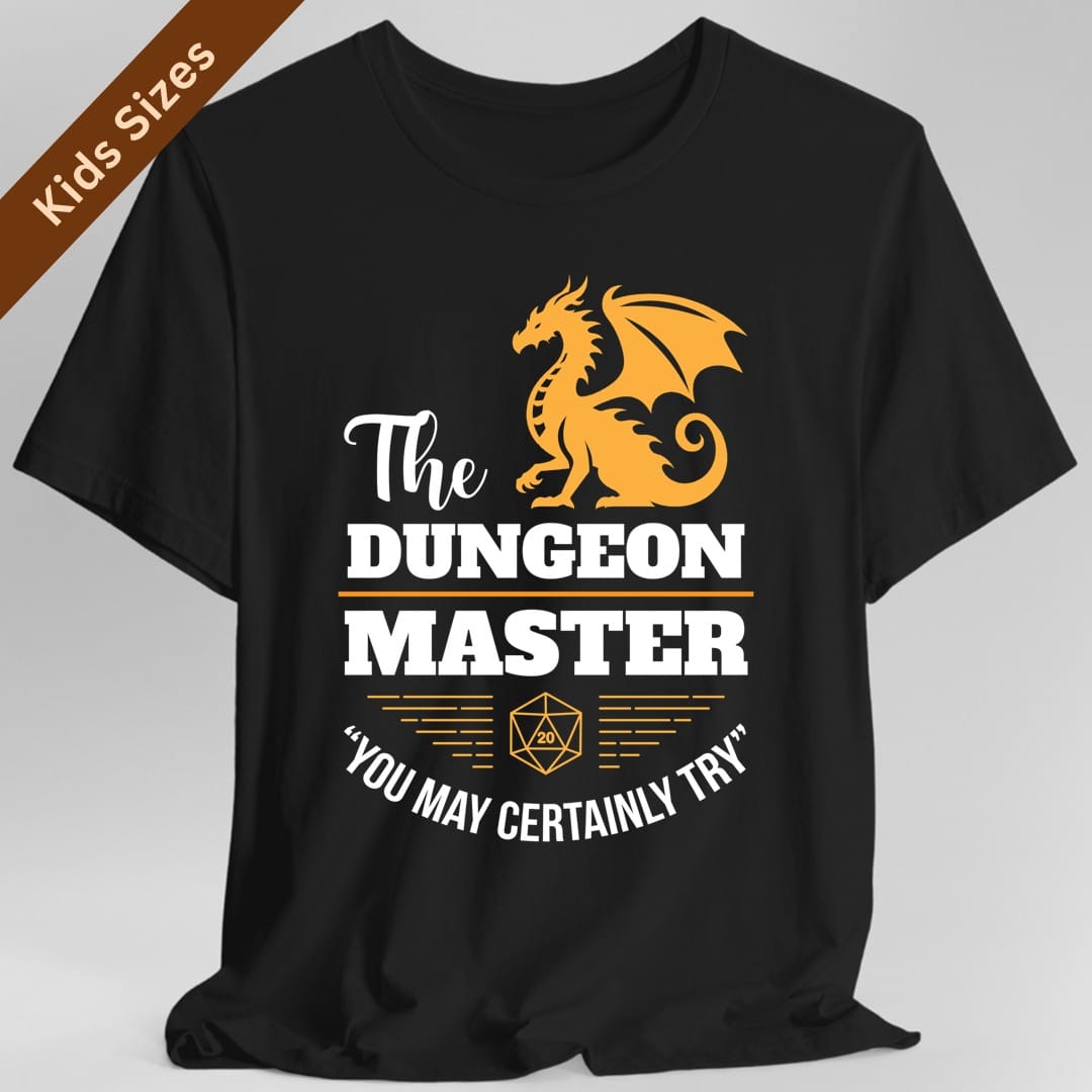Black kids t-shirt. An amber-gold dragon sits with its wings spread at the top. Below it the words "The Dungeon Master" in white, with The in a script hand and Dungeon and Master in tall bold capitals split by a gold line. Underneath, a gold twenty-sided die sits between two fans of gold speed lines, and a curved white line reads "You may certainly try." Vintage badge layout in white and amber.