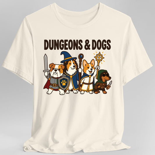 Natural t-shirt. The design reads "DUNGEONS & DOGS" in heavy dark brown letters across the top. Below, four cartoon dogs stand together as an adventuring party: a bulldog knight in grey armor and a red cape with a sword and paw-print shield, a collie wizard in a blue hat and robe with a staff, a corgi cleric in white and gold robes raising a glowing sun symbol, and a dachshund rogue in a green hood with a dagger.
