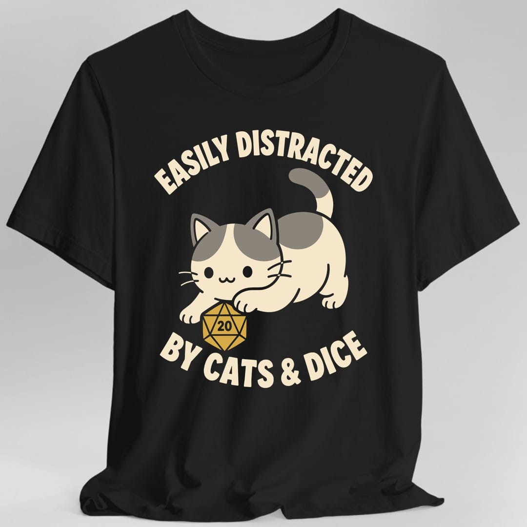 Black t-shirt. The design reads "EASILY DISTRACTED" arched above and "BY CATS & DICE" curved below, in cream letters. Between them a cream and grey cat crouches playfully with its back end raised and tail curled, one paw reaching for a gold twenty-sided die resting on the ground with the number 20 on its top face. Soft rounded cartoon art.