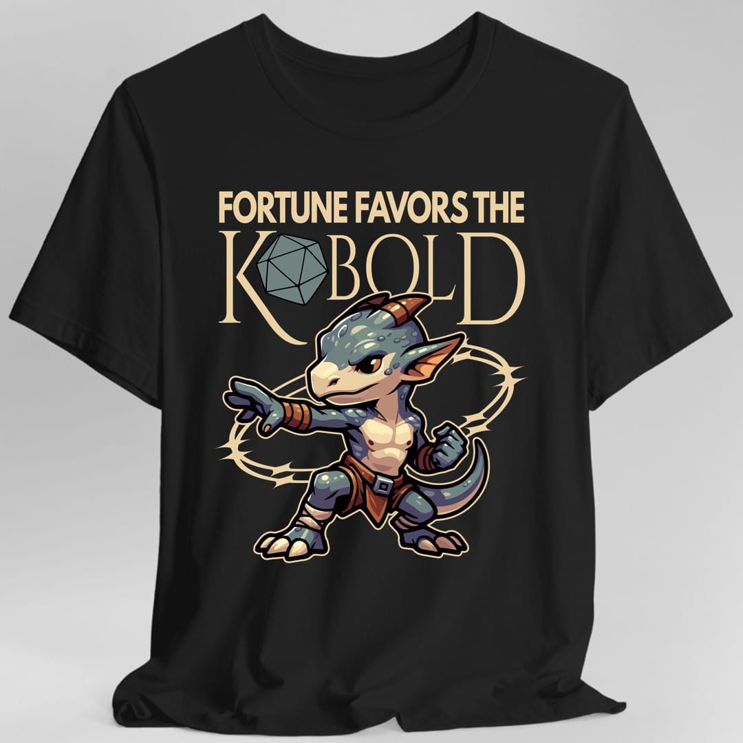 Black t-shirt. The design reads "Fortune favors the Kobold" across the top, with a twenty sided die standing in for the letter O in Kobold. Below it a small scaled kobold with horns, big ears and a long tail plants its feet in a fighting stance, one fist clenched and the other arm flung out, with a ring of light behind it. Bold outlined cartoon art in blue-green, cream, rust and tan.