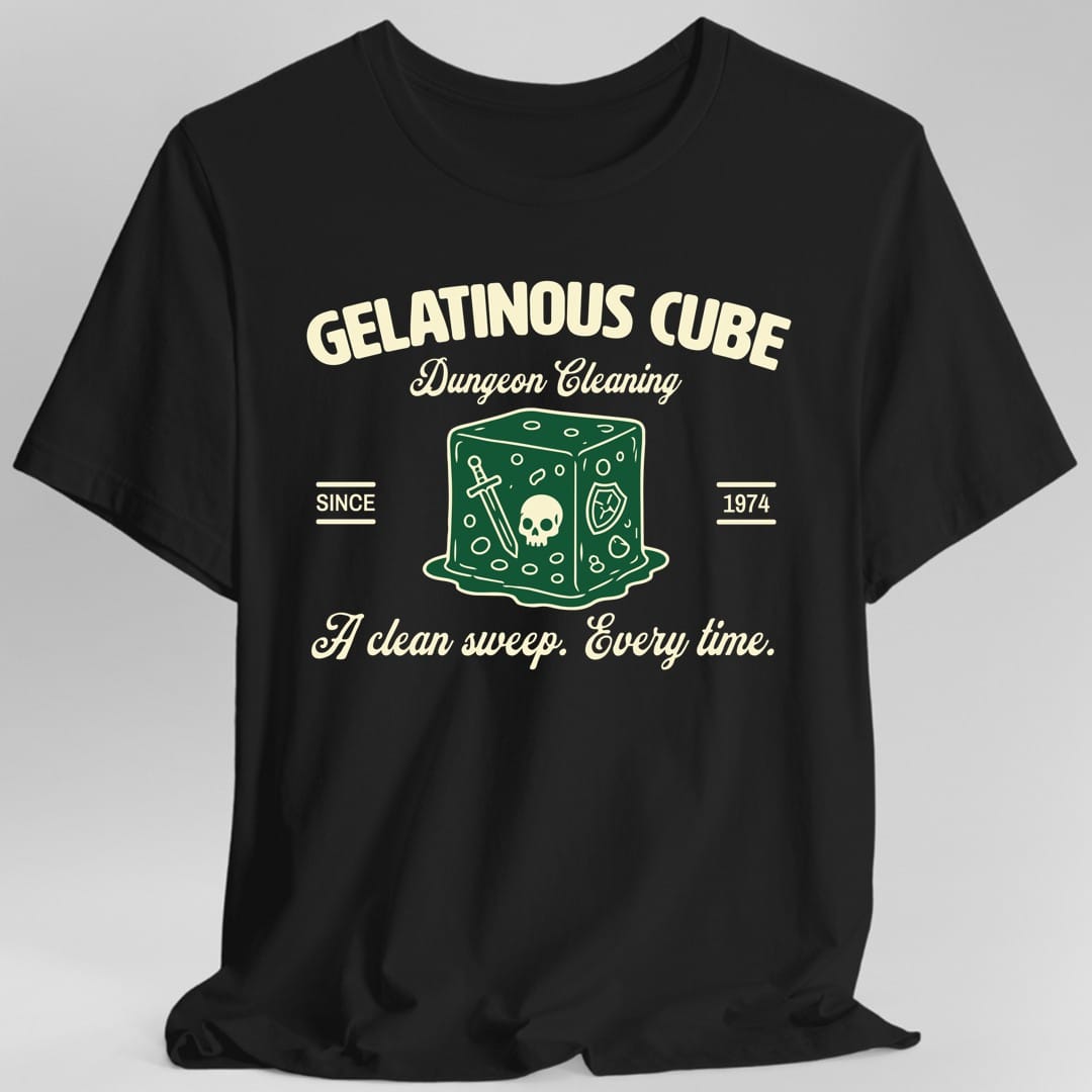 Black t-shirt. The design reads "Gelatinous Cube" in bold arched capitals, "Dungeon Cleaning" in script below it, "Since 1974" split to the left and right, and "A clean sweep. Every time." in script across the bottom. In the center is a green gelatinous cube with a sword, a skull and a shield suspended inside it, melting into a puddle. Vintage trade logo art in green and cream.