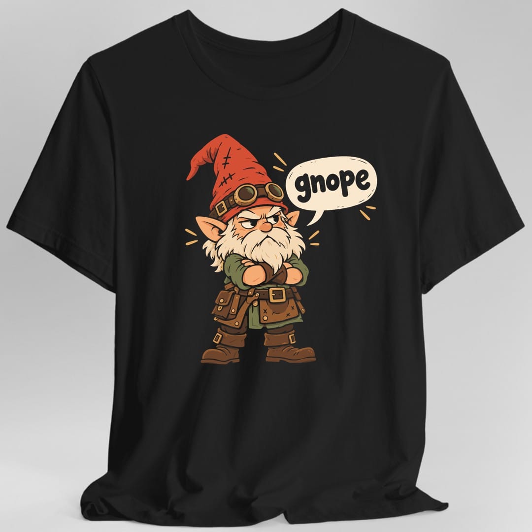 Black t-shirt. The design shows a grumpy gnome with a long cream beard and heavy eyebrows, arms folded, scowling straight ahead. He wears a tall red pointed hat patched with stitches, brass goggles strapped around it, a green shirt, a brown leather apron heavy with buckles, and chunky boots. A cream speech bubble beside his head reads gnope in soft lowercase letters. Cartoon style with gold accent marks.