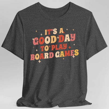 The same Good Day to Play Board Games, groovy design, on a dark heather t-shirt.