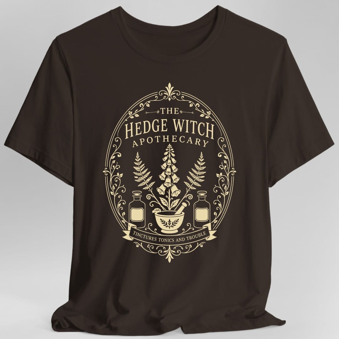 The same Hedge Witch Apothecary label design, on a dark chocolate t-shirt.