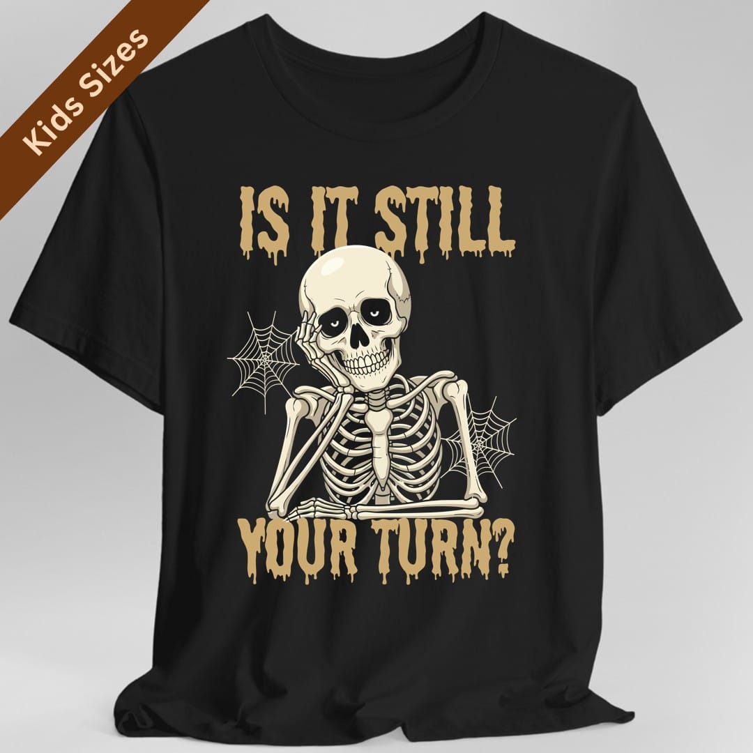 Black kids t-shirt. Reads "Is it still" across the top and "Your turn?" across the bottom in gold capitals with paint dripping from them. Between them a skeleton sits slumped with its chin propped on one hand, elbow on its knee, cobwebs strung between its bones. Cream and gold.