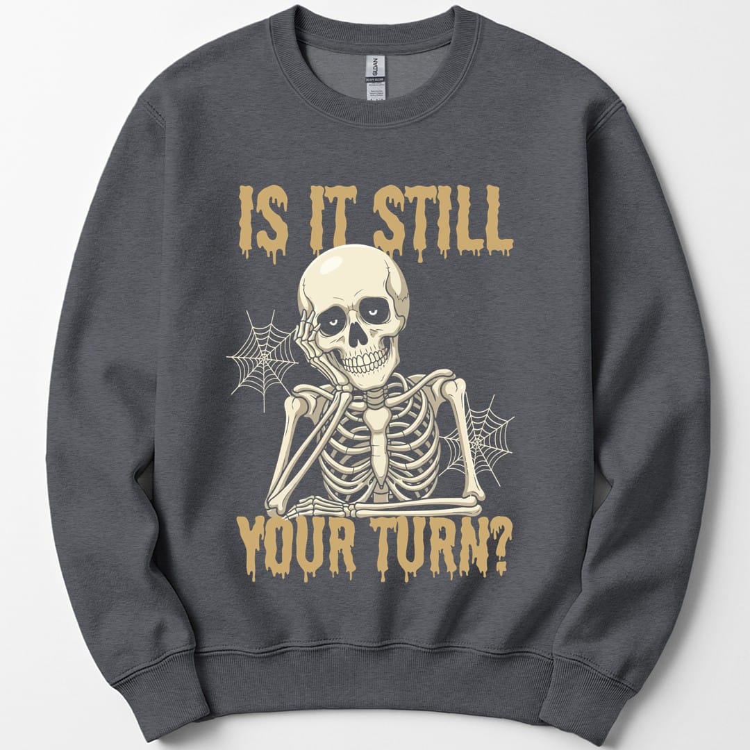 The same Is It Still Your Turn skeleton design, on a dark heather sweatshirt.
