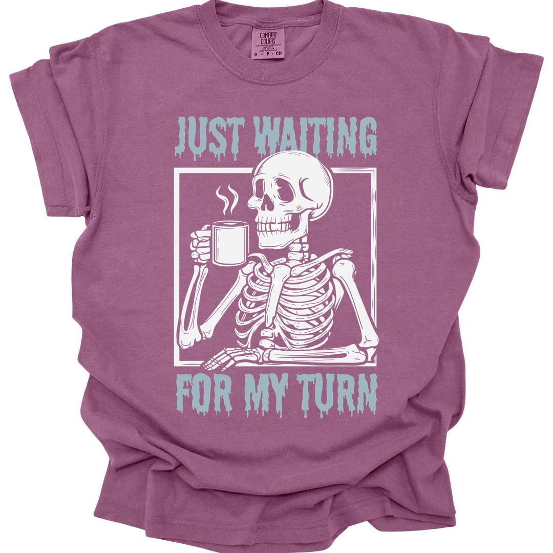 The same Just Waiting For My Turn skeleton design, on a berry t-shirt.