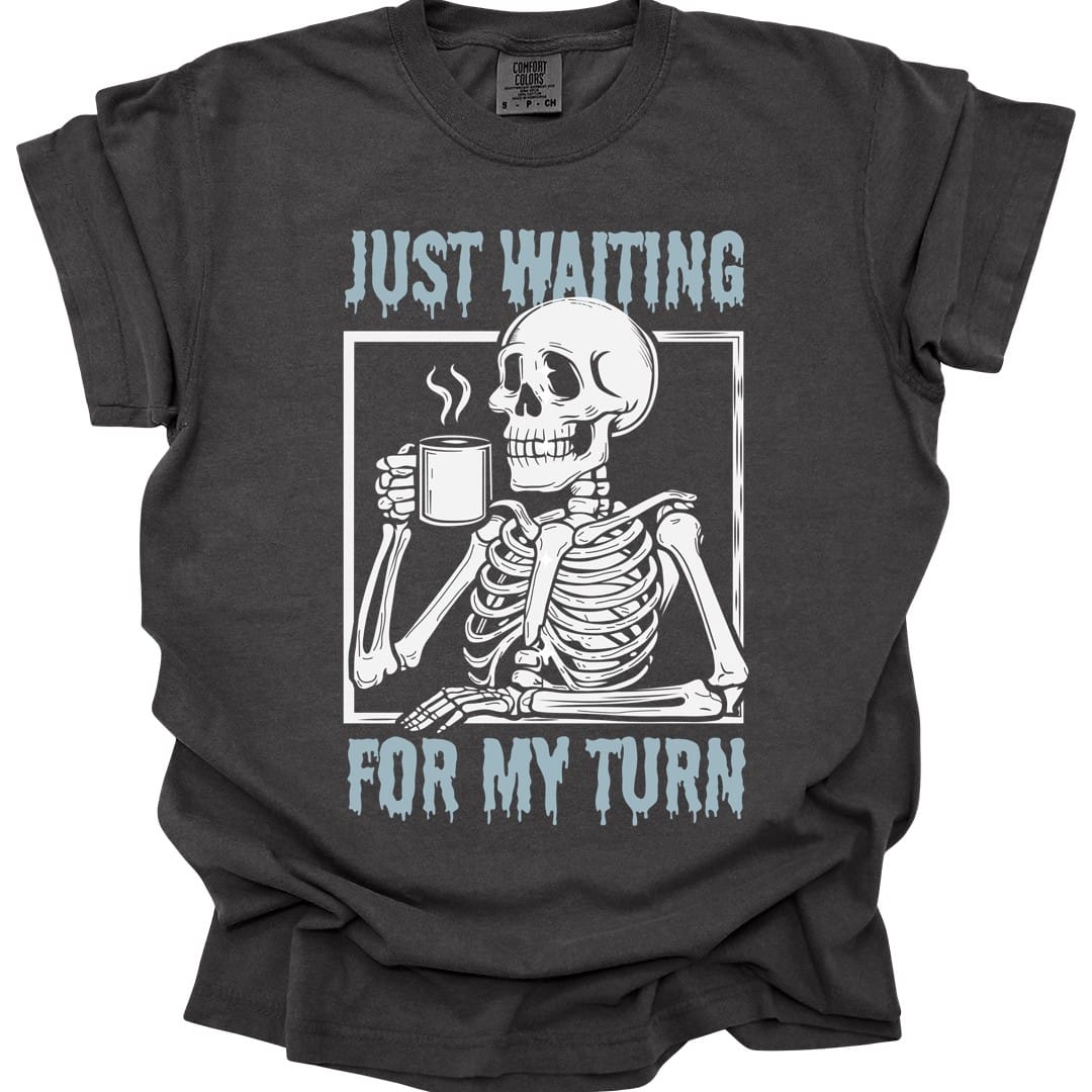The same Just Waiting For My Turn skeleton design, on a pepper t-shirt.
