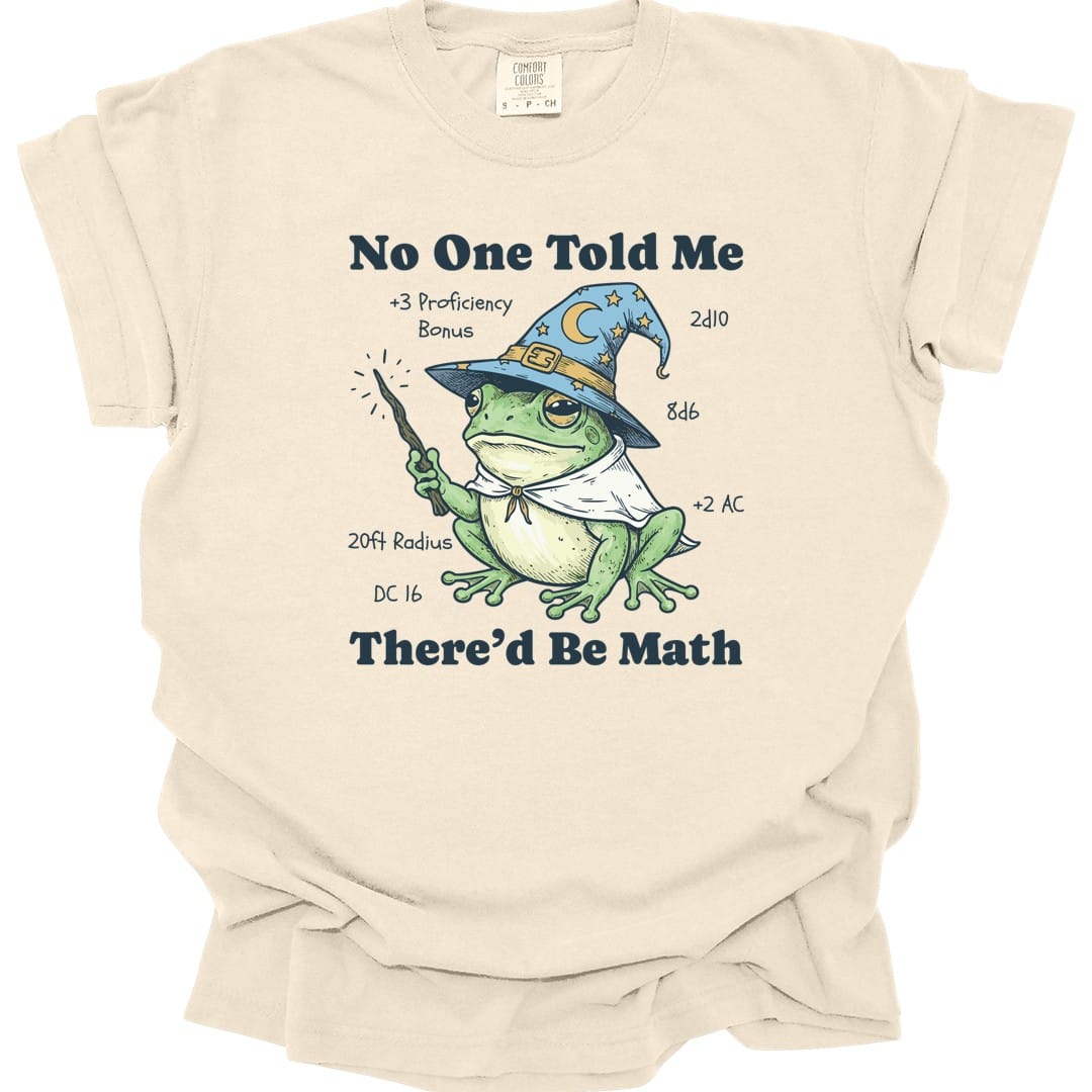 Ivory t-shirt. Reads "No one told me" across the top and "There'd be math" across the bottom in navy capitals. Between them a green frog sits wearing a blue starry wizard hat and cape, holding a wand. Game notes float around it reading "+3 proficiency bonus", "2d10", "8d6", "+2 AC", "20ft radius" and "DC 16".