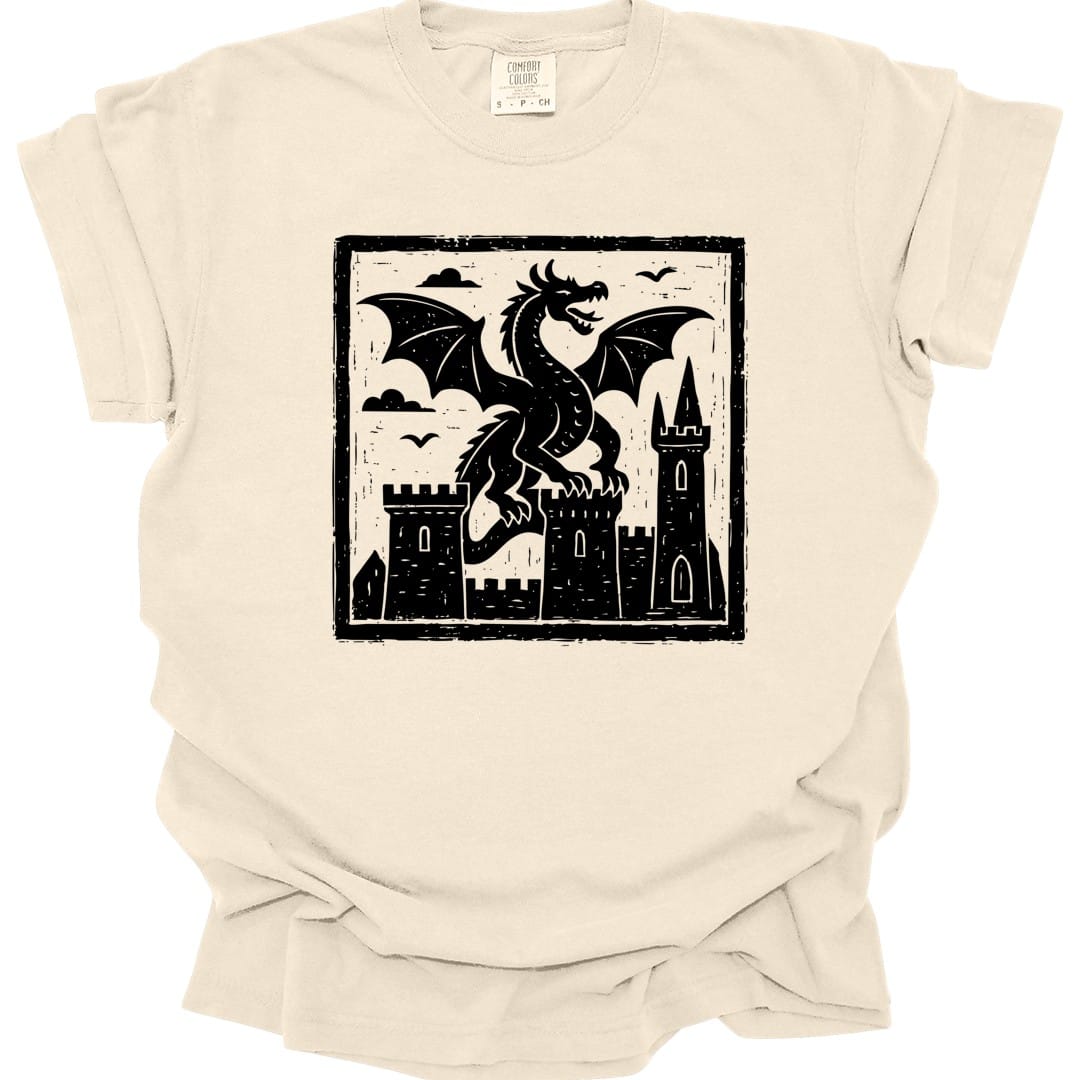 Ivory t-shirt. A square framed woodcut: a dragon with spread wings stands between two stone castle towers, with birds in the sky and hatched clouds behind. Heavy carved black line work filling the frame. No words.