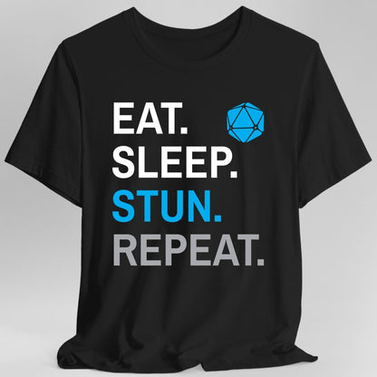 Black t-shirt. Four words stacked in heavy block capitals on four lines: "Eat." and "Sleep." in white, then "Stun." in azure blue, then "Repeat." in gray. A azure blue twenty-sided die sits in the top right corner beside the word Eat. All type, no illustration.