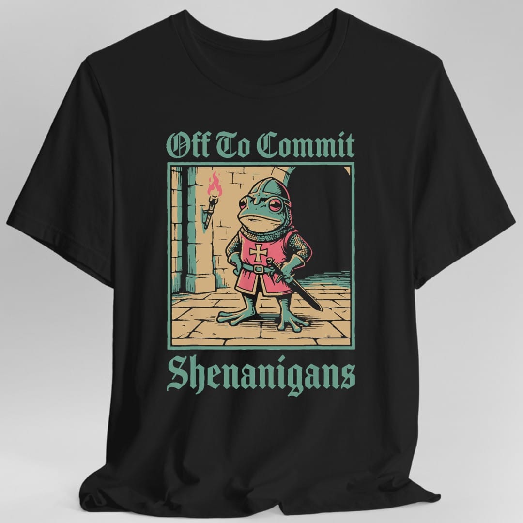 Black t-shirt. The design reads Off To Commit in dark green blackletter across the top and Shenanigans in the same lettering across the bottom. Between them a square framed scene shows a frog in a chainmail coif and a red tunic with a pale cross, hands on hips, holding a sword point down. It stands on flagstones in a stone archway lit by a wall torch, with an open dark doorway behind. Tan, dark green and red, woodcut style.