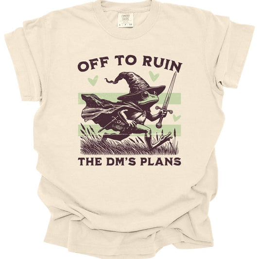 Ivory t-shirt. Reads "Off to ruin" across the top and "the DM's plans" across the bottom in chunky deep plum capitals. Between them a frog in a floppy pointed wizard hat and cape dashes to the right through reeds and cattails, holding a sword aloft. Two pale sage stripes run behind it and three sage hearts float around it. Retro woodcut style in deep plum and pale sage green.