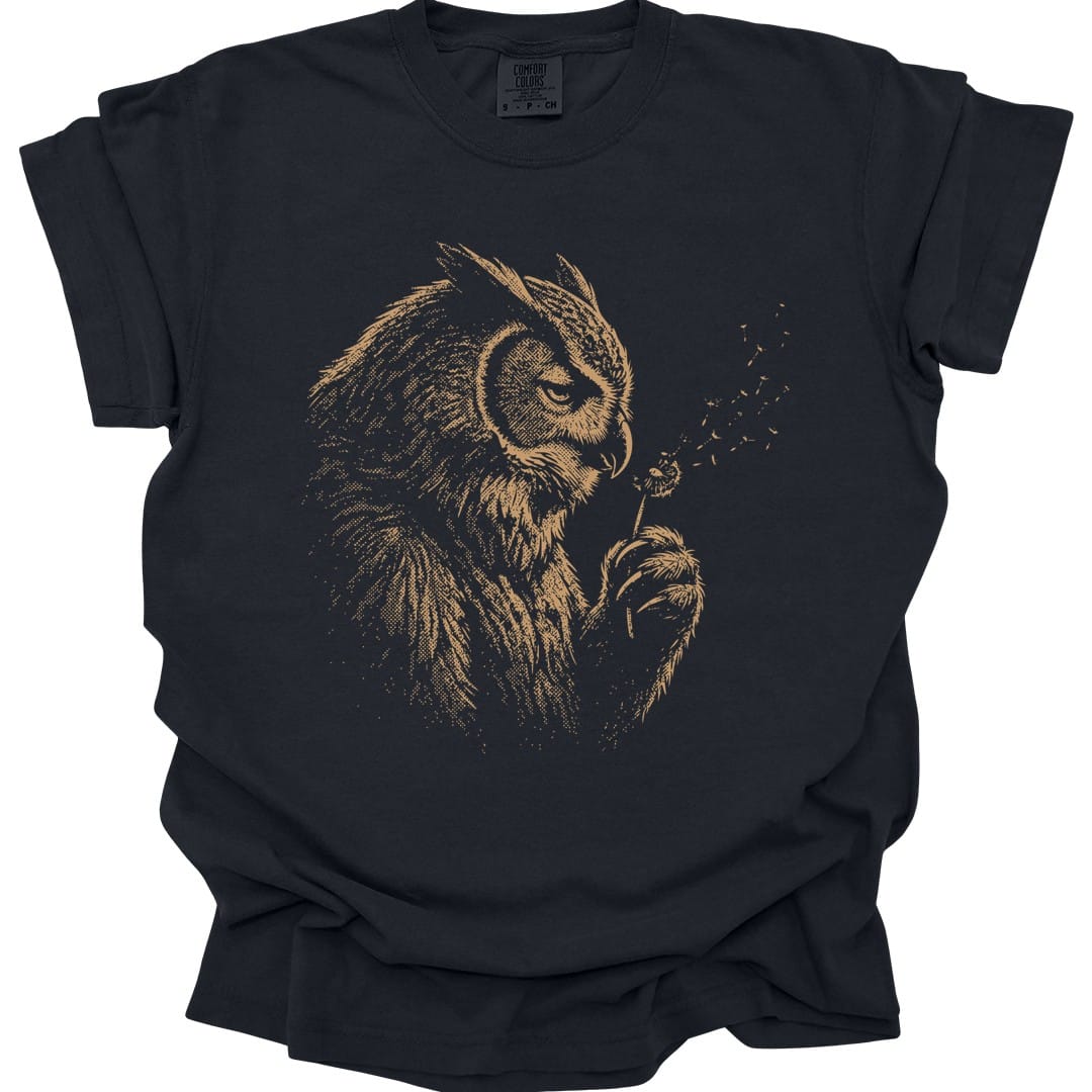 Black t-shirt. An owlbear sits in profile, head bowed, blowing the seeds off a dandelion clock held in one claw, with the seeds drifting away to the right. Drawn in soft faded gold line work, almost ghostly against the shirt. No words.