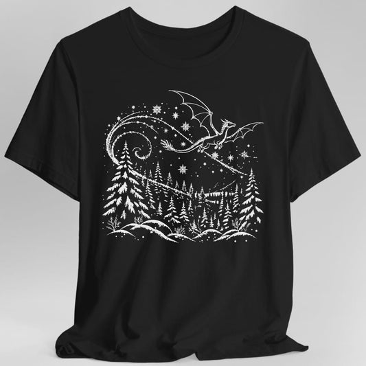 Black t-shirt. A fine white line drawing. A long winged dragon flies across the top of the design, trailing a wide swirling ribbon of stars and snowflakes behind it. Below, a forest of snow laden pine trees rises in rows toward distant hills, with snowy mounds and bare shrubs along the bottom. Delicate white sketch style, no words.