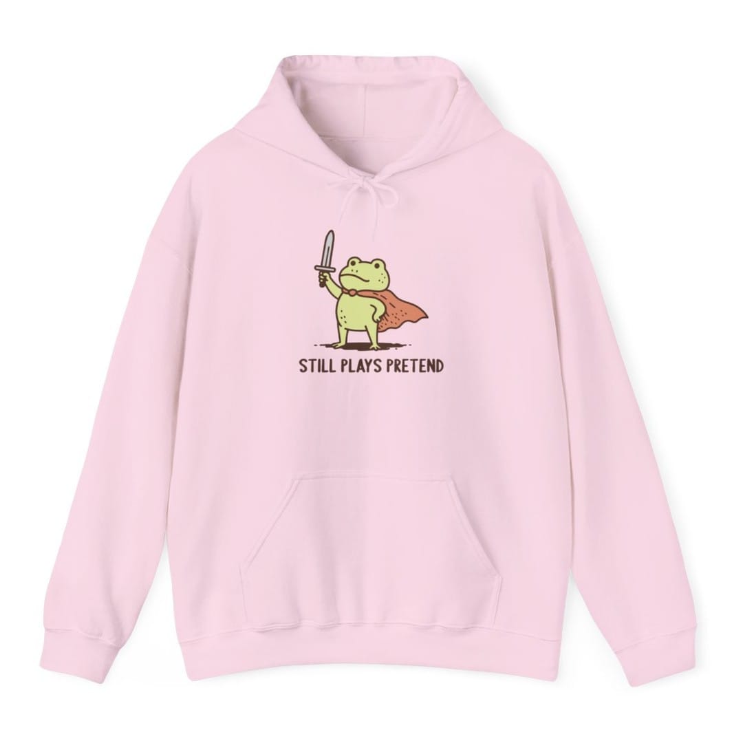 The same Still Plays Pretend frog, small design, on a light pink hoodie.