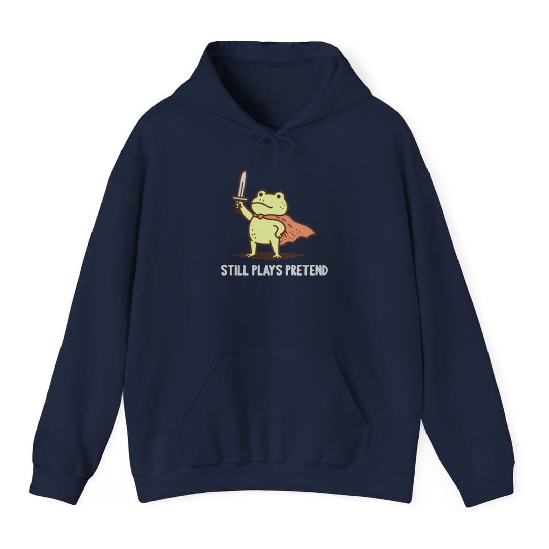The same Still Plays Pretend frog, small design, on a navy hoodie.