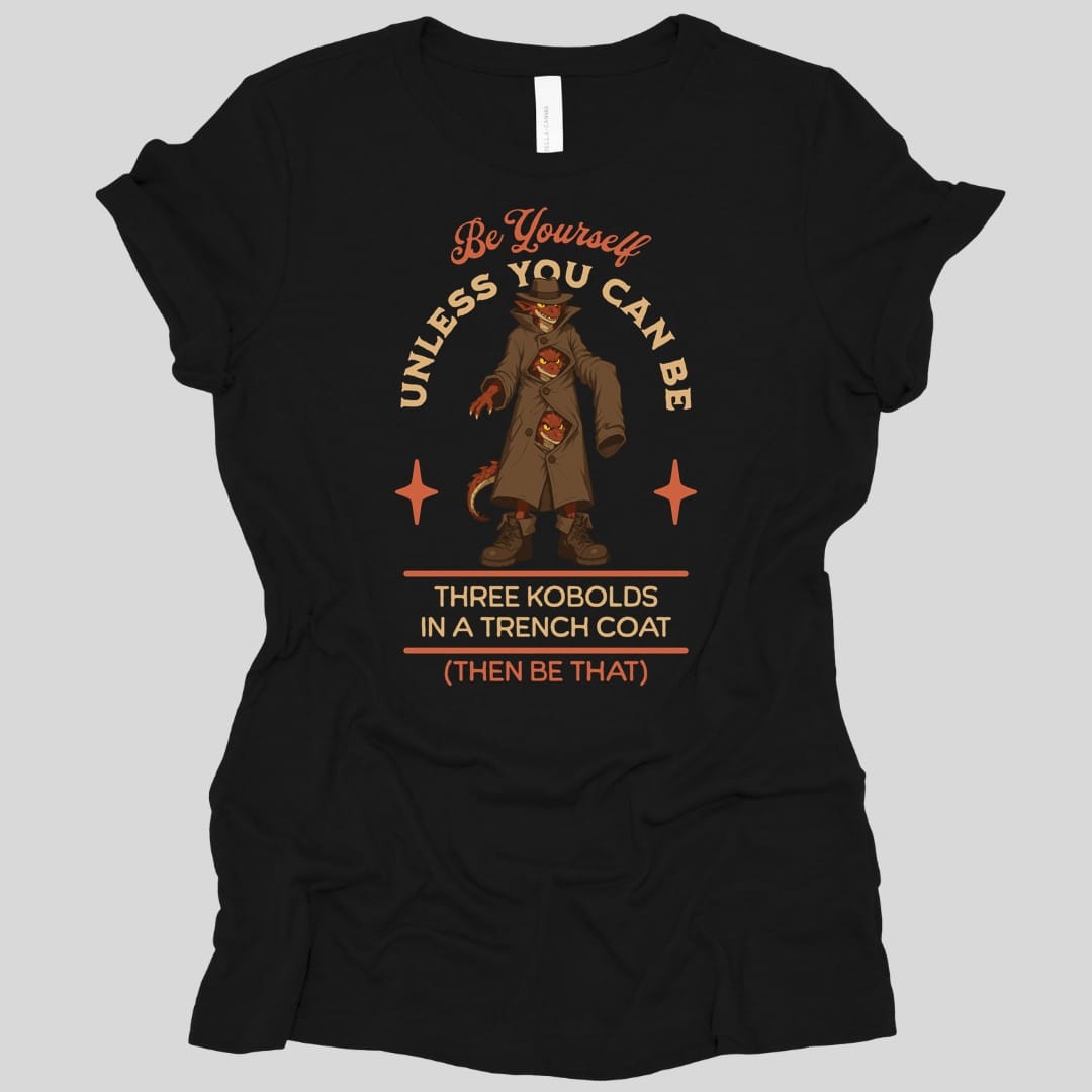 Black women's t-shirt. The design reads "Be yourself" in script at the top, then "unless you can be" curving around the picture, then "Three kobolds in a trench coat" on two lines below, then "(then be that)" at the bottom. In the middle, three small red kobolds are stacked inside one long tan trench coat and a fedora, the top one grinning out from under the hat brim and the other two peering through gaps between the buttons, with a tail poking out of the hem. Bold cartoon art in tan, rust and dark red.